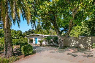 The home is nestled among large trees and lush landscaping, and its simple exterior design still resonates decades later.