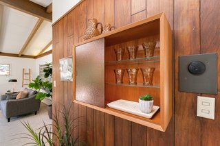 A built-in cabinet with textured glass doors provides storage for extra glassware or supplies for entertaining. The furniture piece is a unique conversation starter in the dining room.