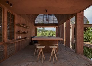 A true example of indoor-outdoor living, the kitchen space is open along one side and at each end. A large center island and simple shelving along the wall complete this minimal space.