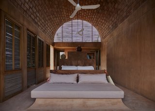 Inside the bedrooms, exposed bricks create a striking atmosphere underneath the barrel-vaulted ceiling. A latticework of reed encloses the roof, allowing for easy circulation of fresh, warm air throughout the space.