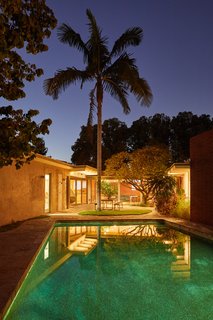 The backyard patio and pool glow in the moonlight, recalling a feeling of glory days from the retro Googie era.