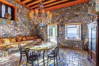 A breakfast area overlooks the terrace and views of the sea. A stunning mosaic of hand-painted majolica tiles canvases the floor and walls, contrasting with custom designed fabrics along the built-in couch.