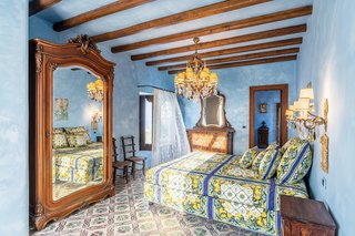 A mirrored armoire reflects the room's charming blend of wood tones and decorative patterns set against sky blue walls. <span style="font-family: Theinhardt, -apple-system, BlinkMacSystemFont, "Segoe UI", Roboto, Oxygen-Sans, Ubuntu, Cantarell, "Helvetica Neue", sans-serif;"><br></span>
