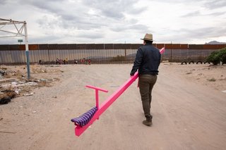 Ronald Rael heads towards the border carrying one half of the three pink teeter-totters.