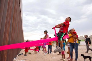 Kids at the U.S.–Mexico border take turns on pink seesaws installed by architecture professor Ronald Rael. 