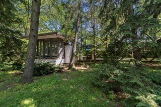 Surrounded by a natural landscape, the low-lying structure appears to hover close to the ground. The simple stucco and wood exterior and rows of windows are characteristic of Wright's other Prairie-house designs built between 1900 and 1914.