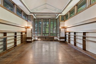 Vertical windows create a dramatic central element at one end of the room. The eyes are also drawn upward by a pitched cathedral ceiling, bordered by wide eaves and clerestory windows running along both sides of the room. 