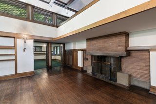 At the opposite end of the living room is a large brick fireplace, with a balcony overlooking the space from a second-story loft. Double glass doors open up to a window-wrapped sun porch.