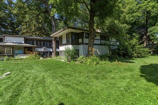 The large backyard offers a grassy area and plenty of mature trees. According to conservation reports, the home was affectionately referred to as the 'Baker Bungalow' by local residents.