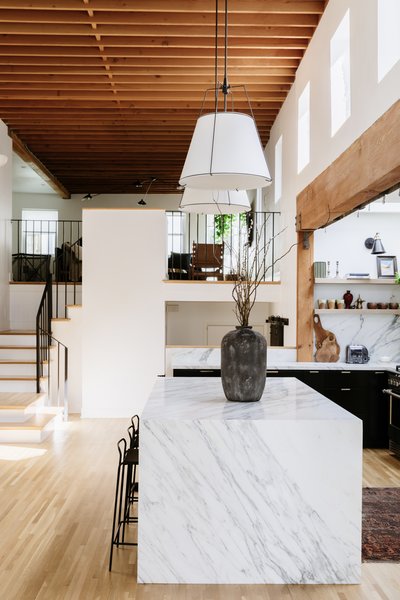 A soaring, wood-beamed atrium is an unexpected surprise upon entering the home. The renovated kitchen features a large marble island that visually grounds the space.