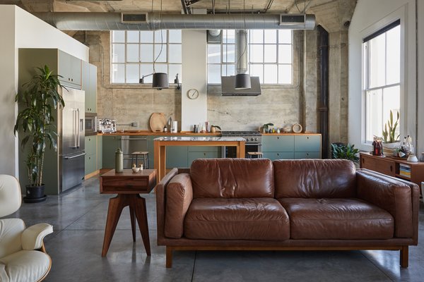 The loft's original open floor plan, 13-foot-tall ceilings, and polished concrete floors remain. A modern, streamlined kitchen is now a central focal point.