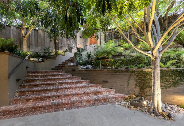 From a gate along the street, brick stairs lead down to a sunken courtyard and the home's main entrance. A separate gated driveway provides access to a two-car garage.