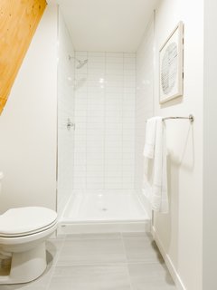 Subway tiles line the standing shower in the crisp, white bathroom.