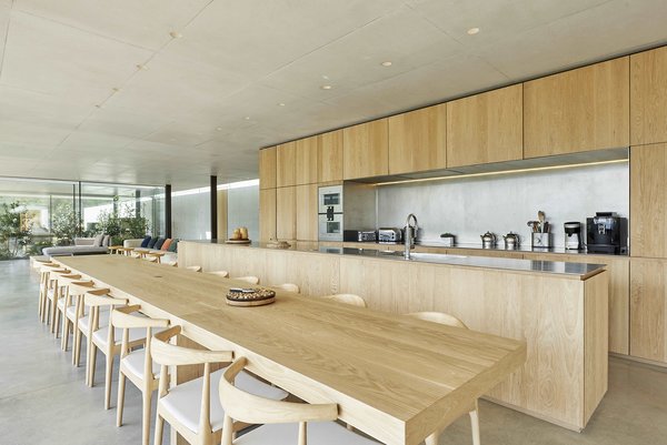 The kitchen and dining area seamlessly flow from the living room. Designed for entertaining, the space offers a 20-person dining table, three Gaggenau ovens, and a massive central island. 