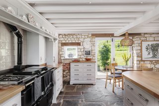 A look at the kitchen, which offers a large range and an abundance of storage. Beamed ceilings, along with stone floors and walls, retain an authentic look within the space.