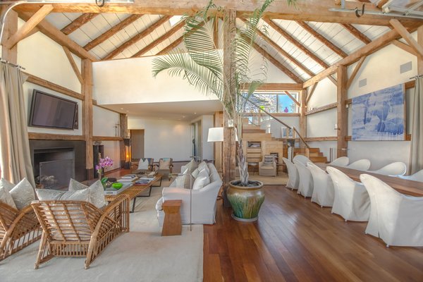 The double-height living/dining room was designed by Tom Flynn. The voluminous space features exposed beams and rafters.