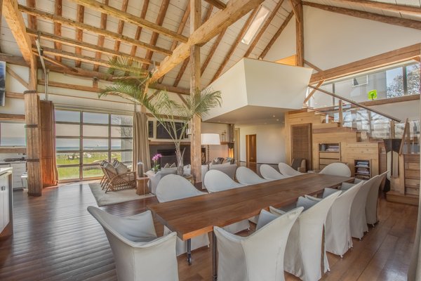 A long wooden table in the formal dining area can easily accommodate 12 guests. Bespoke cabinets and shelves provide storage space underneath the staircase.