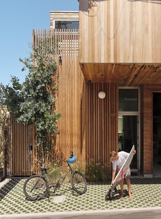 The alley entrance is shaded by a cantilevered volume on the second floor. Turf-block pavers reduce runoff.