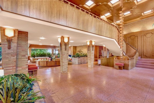 The grand foyer features terrazzo floors, pillars made of Roman bricks, massive teak paneling, and tessellated skylights.