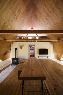 At one end of the first floor, a small bedroom and a bathroom create a private living area for the family. The loft area above houses a small workspace.