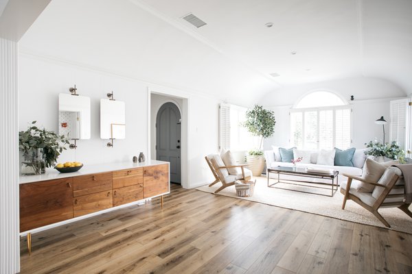 A small foyer opens into the large, luminous living room. The open space is flooded with natural light from several large windows that wrap around the front and side of the home. 