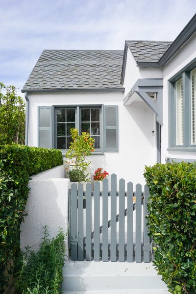 A painted, picket-fenced gate welcomes visitors at the home's main entrance. Lush landscaping around the home adds both privacy and charm.