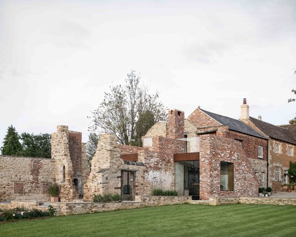 Located about an hour northwest of London in Northamptonshire, a Grade II listed Victorian home was extended to encompass an adjacent cattle barn and historic ruin.