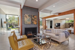 Living Room, Sofa, Vinyl Floor, Ceiling Lighting, Chair, and Coffee Tables The living room sits just behind the kitchen and features an original masonry block fireplace. A cozy family room is tucked into the corner.