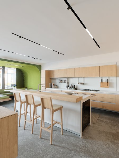 The Bulthaup kitchen also features Calacatta quartzite countertops from Stone Fleury. A Float console table by Aleksandra Zee hangs along a wall opposite the bar stools.