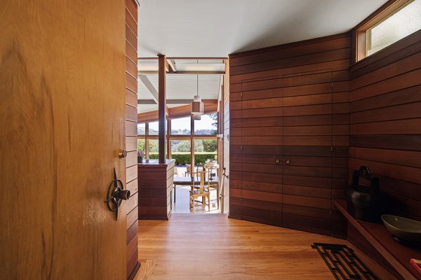 Dark wood clads the walls of the entranceway, which leads to a bright, spacious living room.