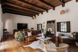 A large living area sits in the center of the home and looks out onto the courtyard. Features of the space include an original timber-beamed ceiling and hardwood floors.