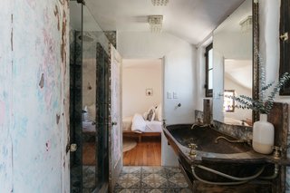 The bathroom features a tiled floor and shower, as well as a custom-made sink and vanity.