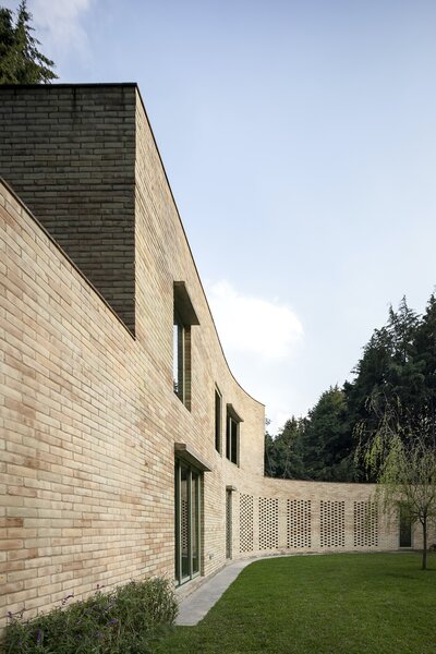 The curved brick wall was formed in relation to the pine forest on which the property is situated, and it continues throughout the main residence as an interior partition.