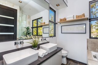 Each of the four and a half bathrooms located in the main house is dressed in designer finishes. In addition to a double vanity, the primary bath also presents an oversize glass shower.