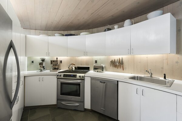 Light-hued timber lines the walls and ceiling in the kitchen, contrasting with the white cabinetry.