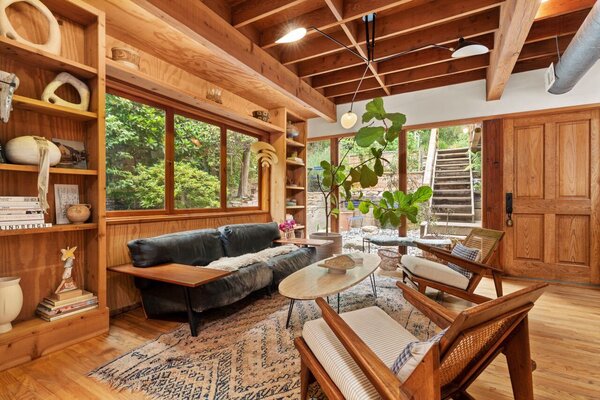 Upon entry is a sun-kissed living area featuring wood-clad walls with custom built-in shelving.