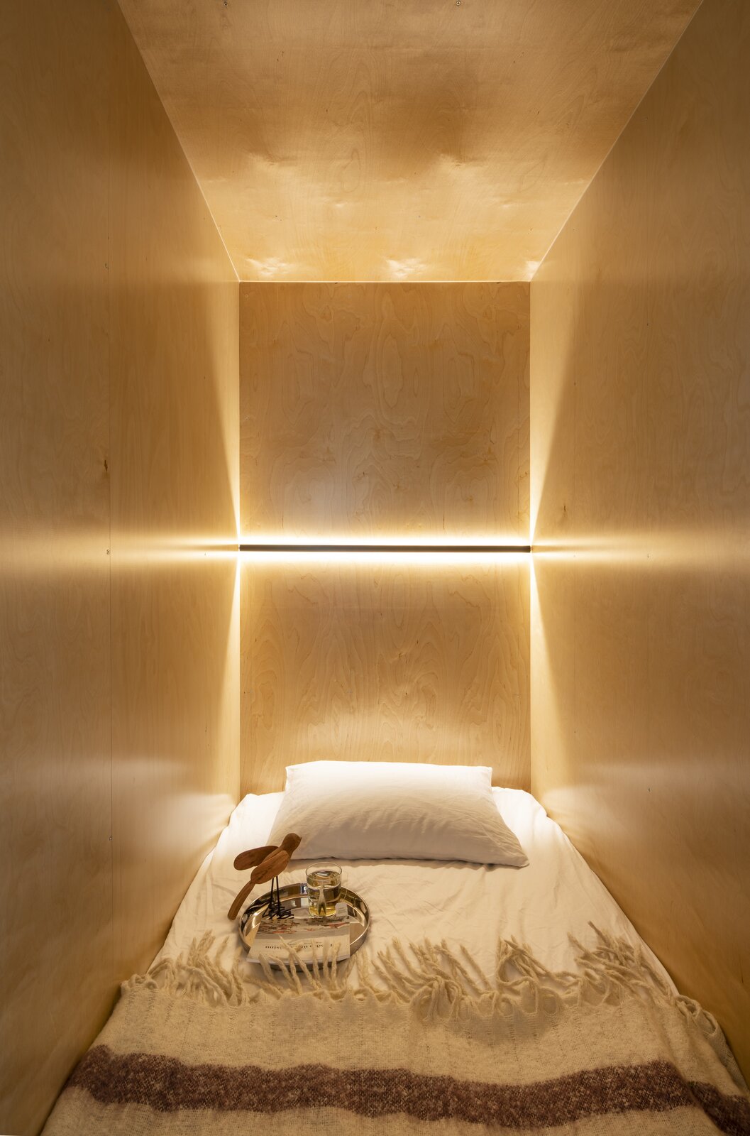 The sleeping nook is just large enough to house a twin-sized mattress. Lighting is recessed into the maple-finished wall panels, and pull-out storage is concealed beneath the bedframe.