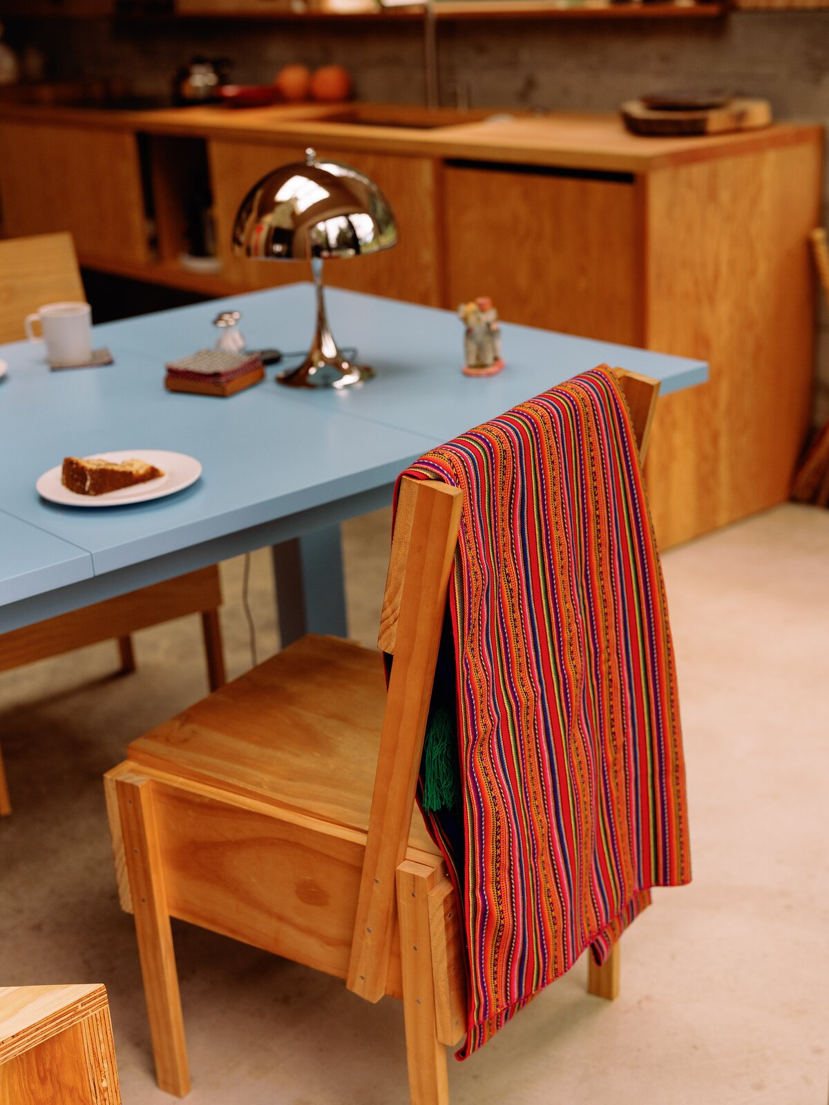 The east-facing kitchen is the brightest room in the house. A Louis Poulsen lamp sits at one end of the table, which doubles as the couple’s desk. There are no drawers or cabinets, just sliding panels to hide things. 