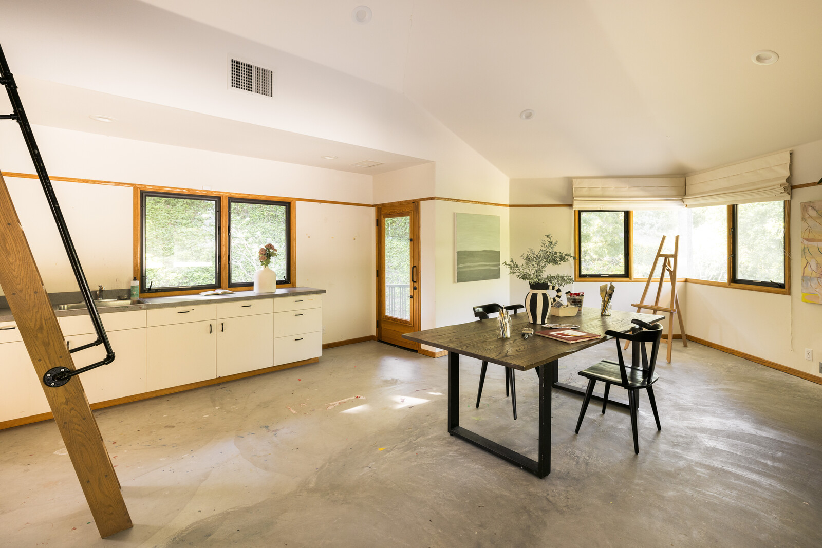 The east wing of the home features a separate entrance that leads to a downstairs apartment, complete with its own living area, bathroom, and large studio space.