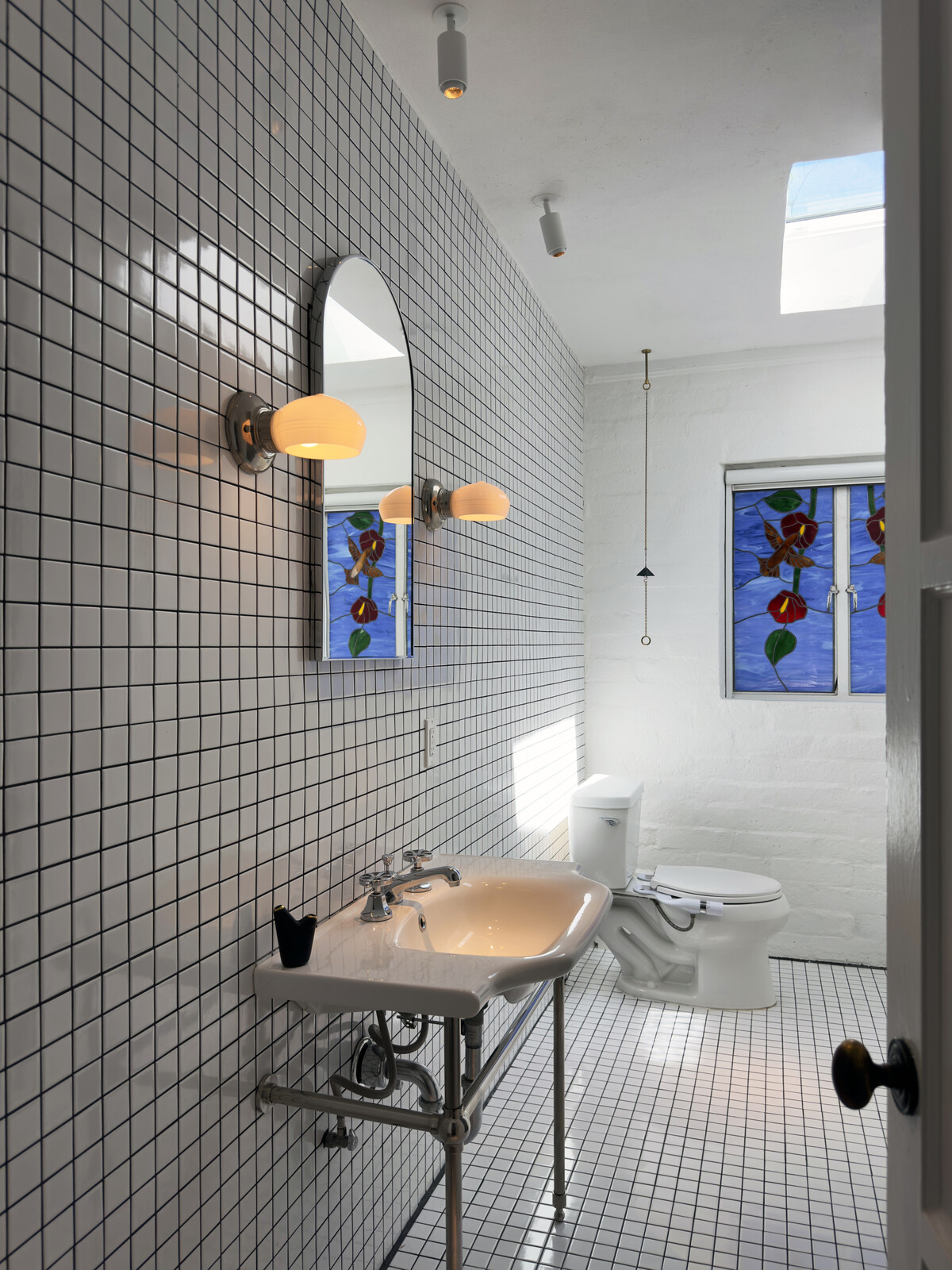 The bathroom has floor-to-ceiling tile and a stained-glass window installed by a previous owner.