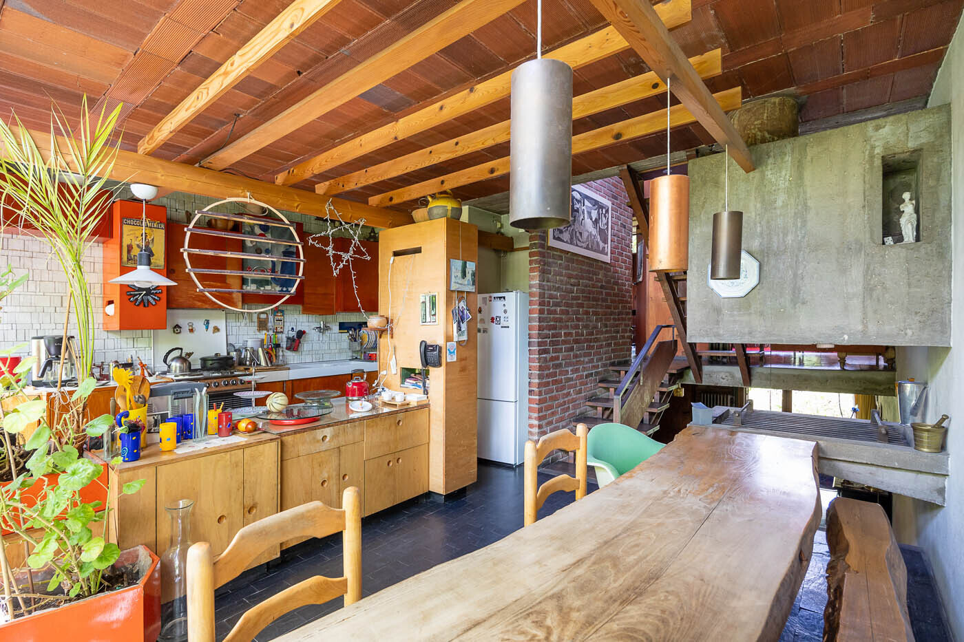 The bright, airy dining room features a rough-cast concrete fireplace and is steps from the bespoke fitted kitchen with cleverly arranged wooden cupboards.