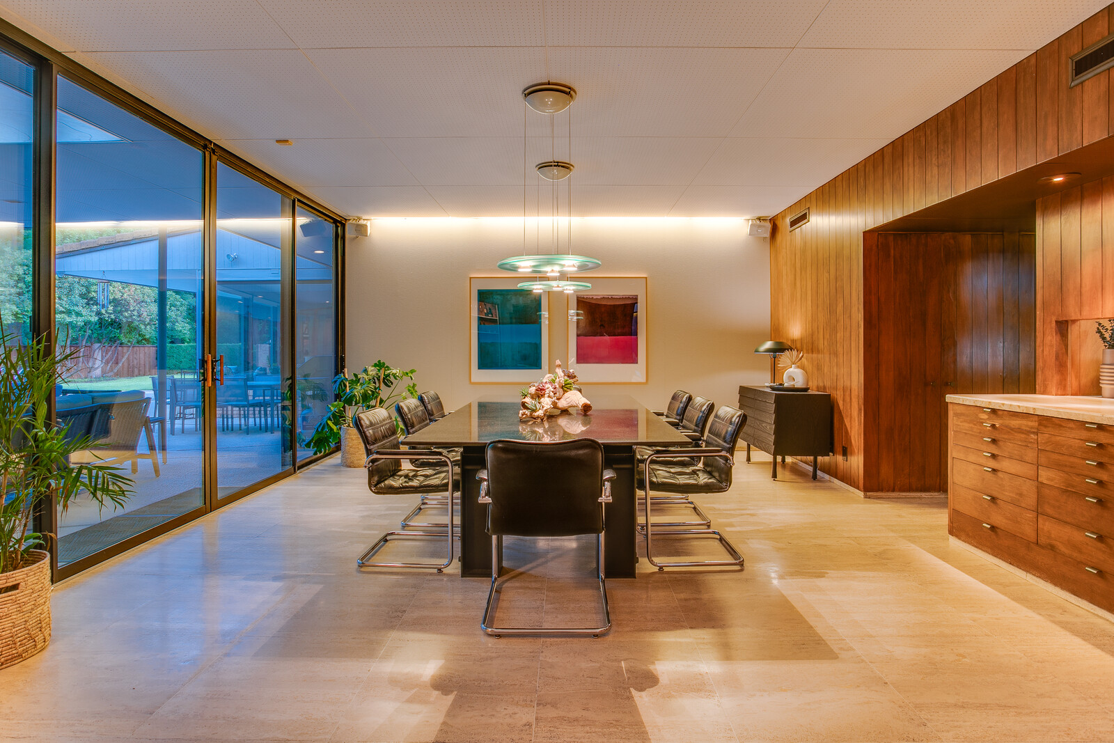 Floor-to-ceiling windows and glass doors continue into the dining area and open up to the concrete patio and pool awaiting in the backyard.