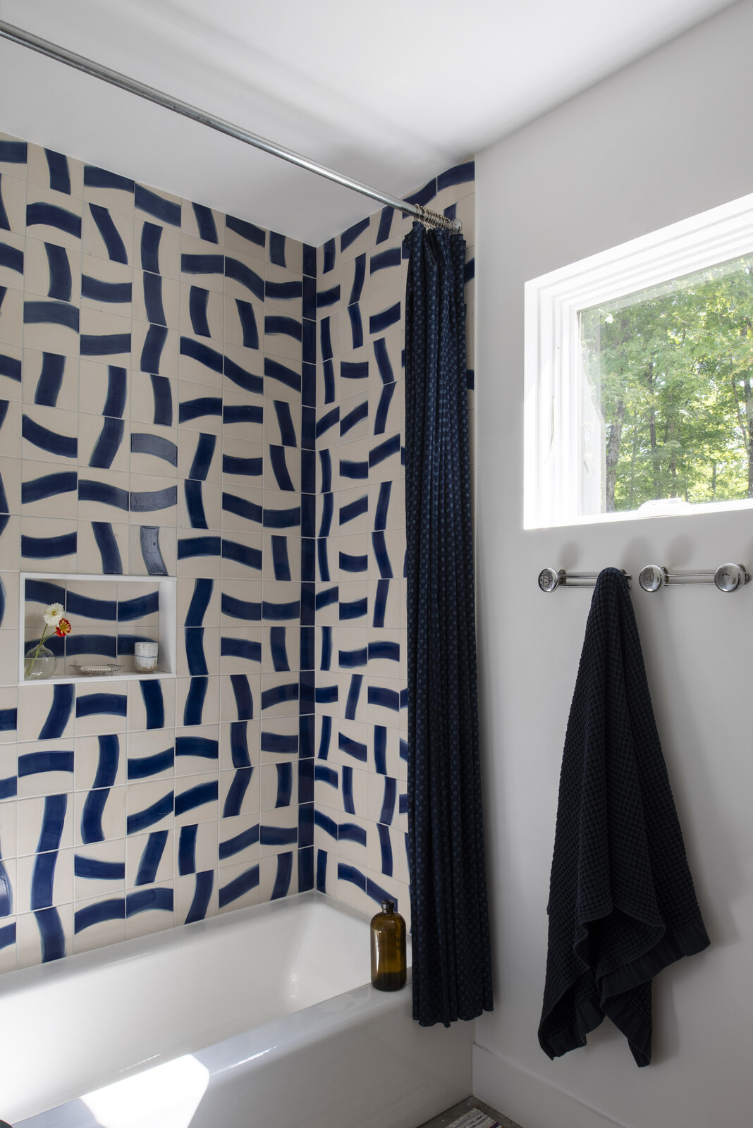 A tiled shower in one of the two bathrooms presents a playful pop of pattern and color.