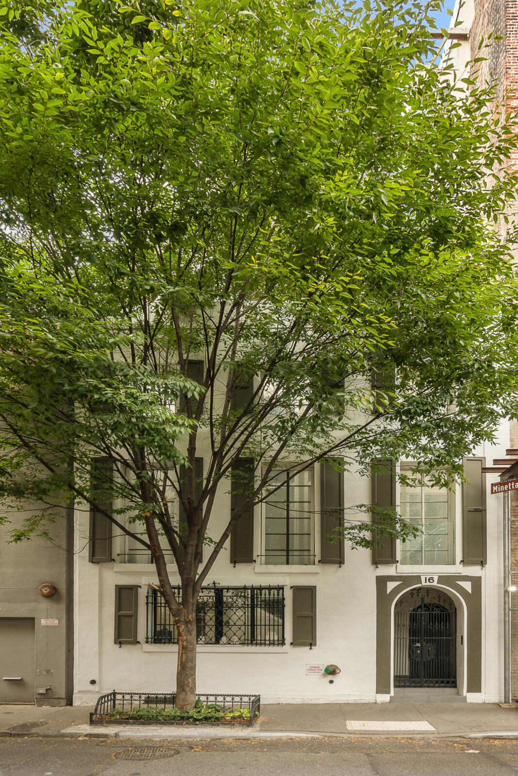 The historic home rests behind a soaring, leafy tree in a landmarked area of Greenwich Village.
