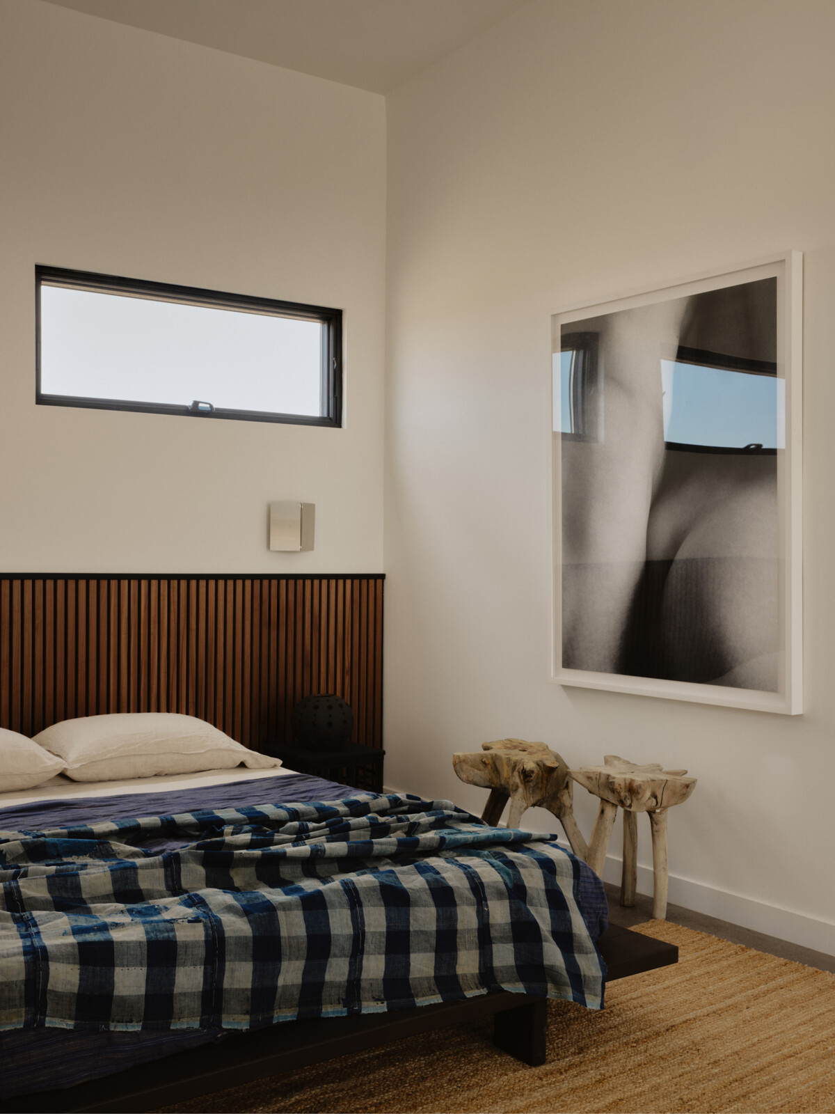 A ceramic piece by Kevin Willis sits on the nightside beside an antique indigo boro cloth sourced from Japan. The metal sconces are from Linchen.