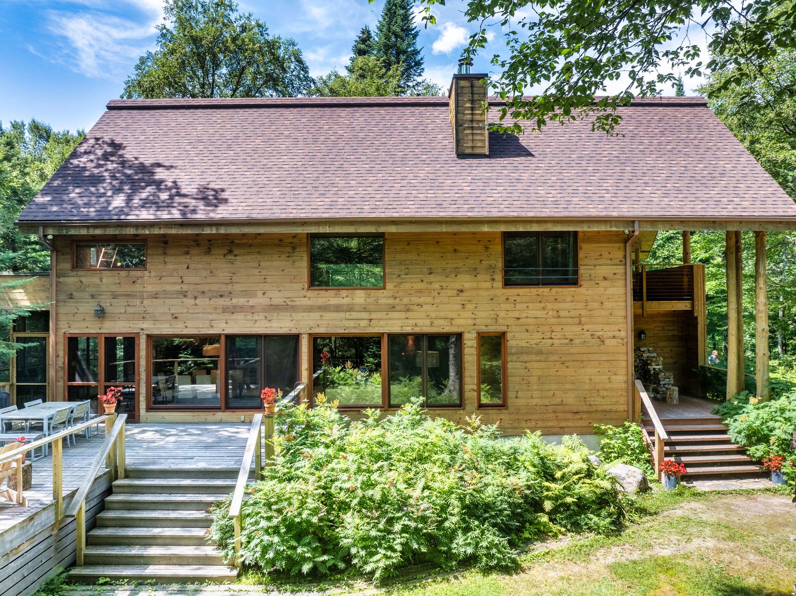 Designed by Pierre Thibault, the woodsy home connects to its surroundings with covered decks, floor-to-ceiling windows, and organic materials.