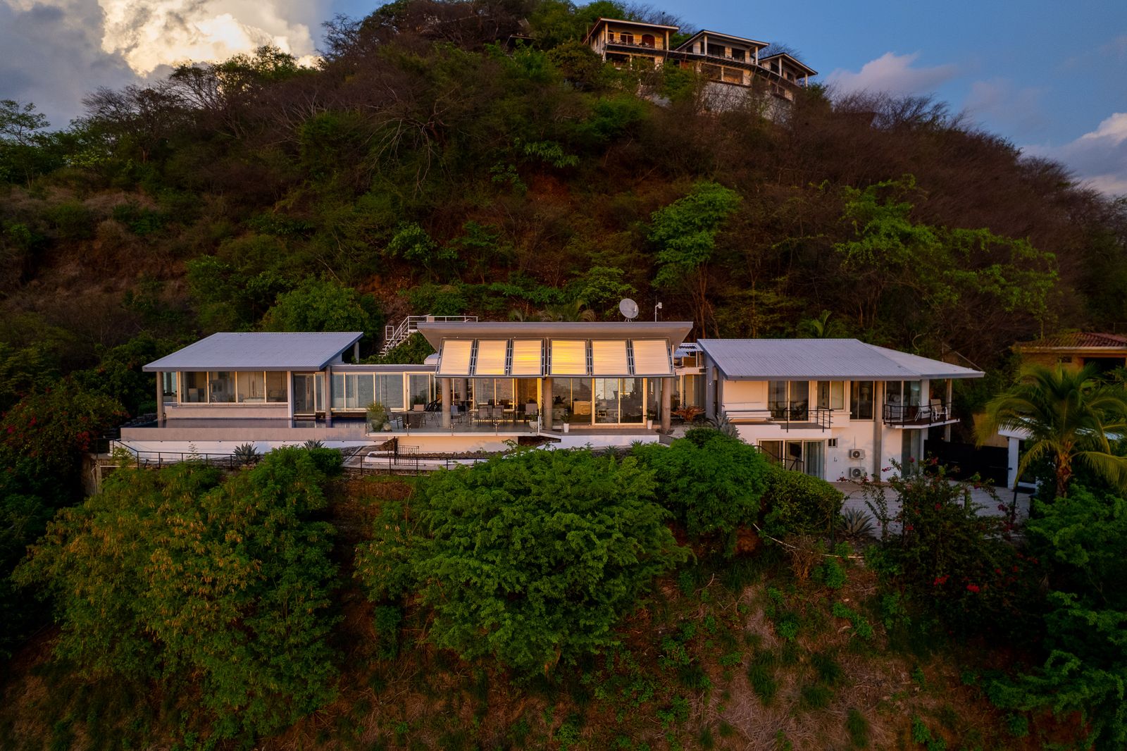 The glass-encased house frames views of its rocky site, the surrounding jungle, and the nearby ocean at Playas del Coco.
