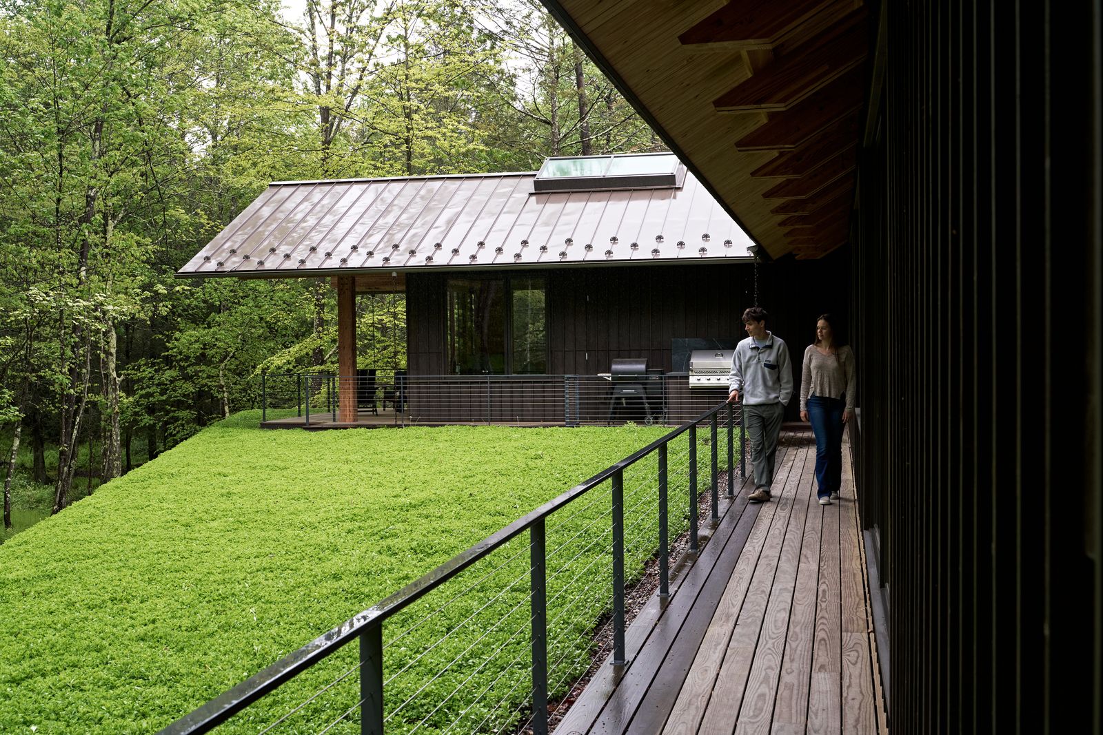 The cedar-clad pavilion hovers above a bluestone base. A covered terrace with a fireplace allows the family to enjoy the outdoors even in colder months. 