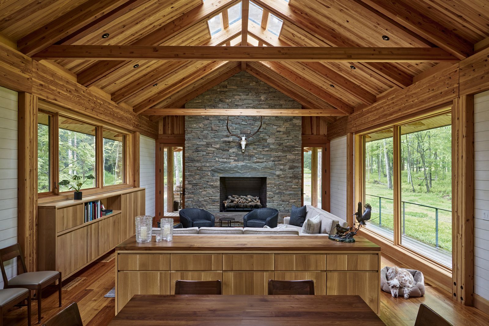 In the double-height living space, Marvin windows stretch nearly floor to ceiling, capturing light even on rainy days and offering panoramic views across the forest. The Douglas fir frame remains exposed throughout, adding warmth, continuity, and rhythm.