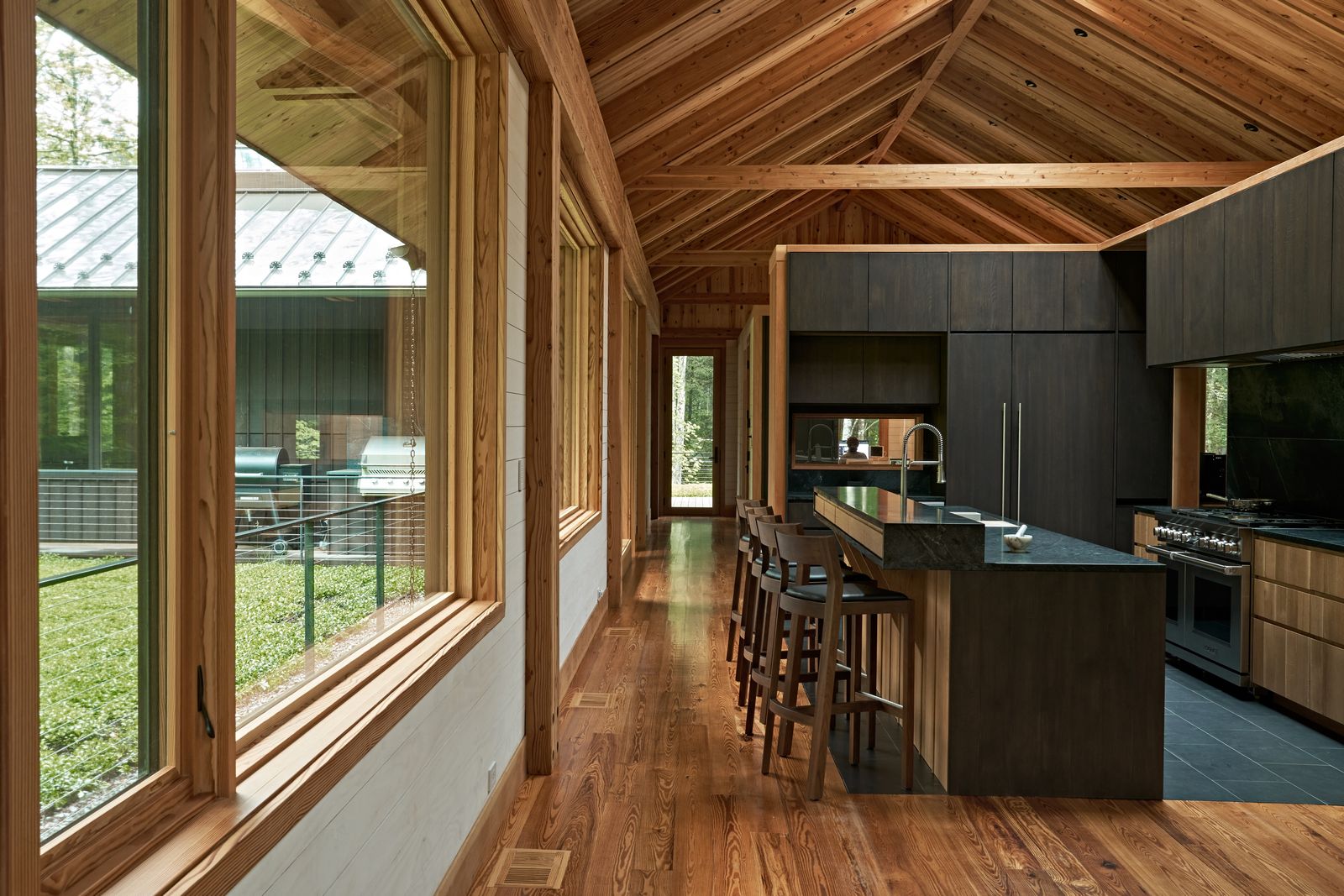 Glulam Douglas fir beams and Marvin Ultimate windows define the treetop kitchen. The windows were selected for their ability to blend with the timber structure, creating what architect Gabe Hodge calls 